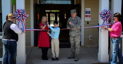 Col. Richard McComb, Joint Base Charleston commander, Matthew Henshaw (middle) and Dacie Wingo (second from left), cut the ribbon, with Sandy Berkos, Forest City Military Communities assistant community manager, and Janel Davis, FCMC relocation specialist, during the opening of new FCMC Community Center March 29, 2013, at Joint Base Charleston – Air Base, S.C. Henshaw and Wingo helped cut the ribbon because they won in the FCMC Art and Essay Contest. Berkeley Miller (not pictured) was also a winner in the Art and Essay Contest. (U.S. Air Force photo/Staff Sgt. Anthony Hyatt)
