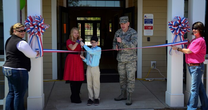 Col. Richard McComb, Joint Base Charleston commander, Matthew Henshaw (middle) and Dacie Wingo (second from left), cut the ribbon, with Sandy Berkos, Forest City Military Communities assistant community manager, and Janel Davis, FCMC relocation specialist, during the opening of new FCMC Community Center March 29, 2013, at Joint Base Charleston – Air Base, S.C. Henshaw and Wingo helped cut the ribbon because they won in the FCMC Art and Essay Contest. Berkeley Miller (not pictured) was also a winner in the Art and Essay Contest. (U.S. Air Force photo/Staff Sgt. Anthony Hyatt)