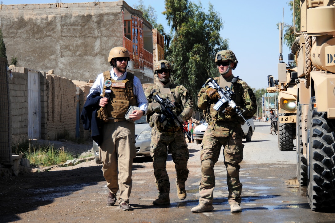 U.S. Army Spc. Michael Jones, right, and U.S. Army Staff Sgt. Roderick Cooper, center, escort Chris Geurtsen, a U.S. Agency for International Development field program officer, upon arriving for a meeting and transitioning ceremony in Farah City, Afghanistan, April 1, 2013. Jones and Cooper are assigned to  Provincial Reconstruction Team Farah.