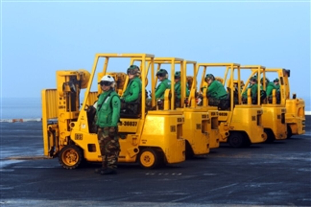 Sailors wait in their forklifts for incoming cargo on the flight deck of the aircraft carrier USS John C. Stennis (CVN 74) during a replenishment at sea on March 30, 2013. The Stennis is deployed to the U.S. 7th Fleet area of responsibility to conduct maritime security operations and theater security cooperation efforts.  