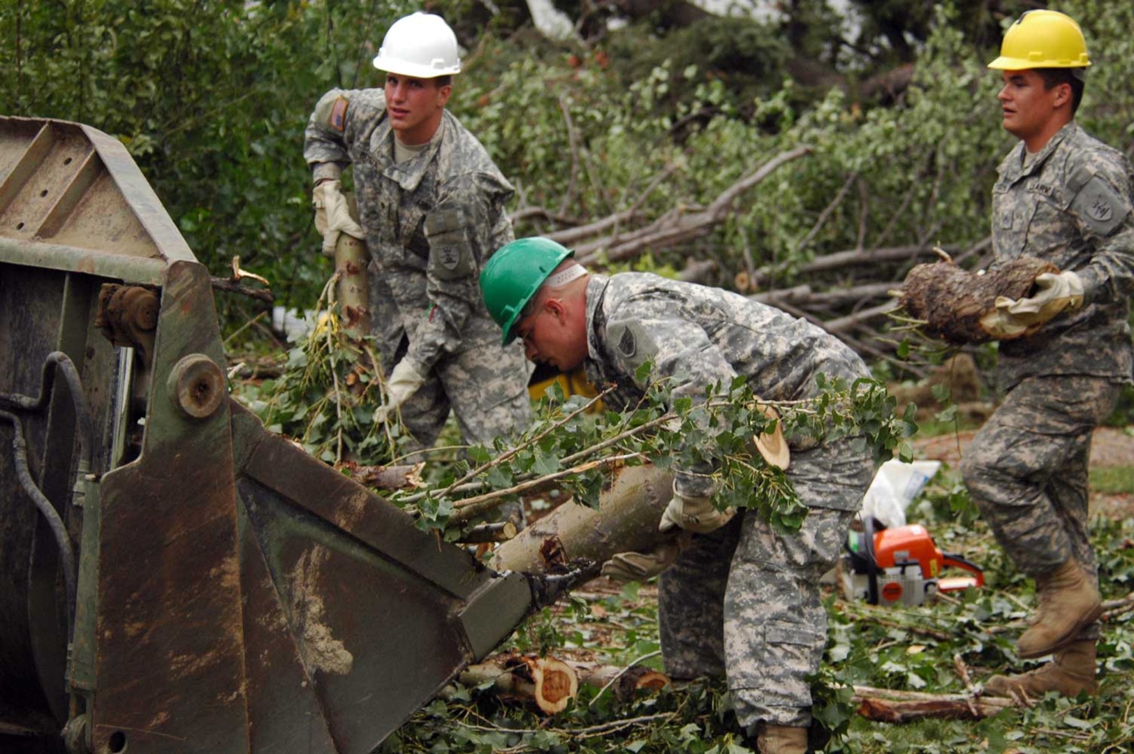 Spc. Ian Busta, Fargo, N.D., 142nd Engineer Combat Battalion; Pvt. Nathan L. Miller, Toronto, S.D., Detachment 2 of the 815th Engineer Company, and Pvt. Kevin J. Iverson, Breckenridge, Minn., 188th Engineer Company, work at clearing downed trees and debris left behind by an F4 tornado that hit Northwood, N.D. on the night of Sunday, Aug. 26.