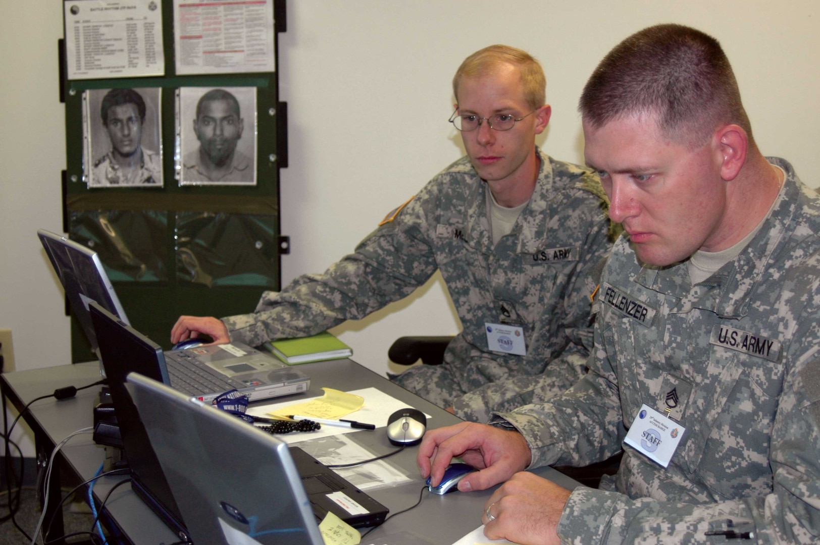 With "most-wanted" posters of terrorists in the background, Staff Sgt. Wallace Fellenzer and Staff Sgt. Jason McCoy of the Virginia Army National Guard conduct intelligence analysis operations on Sept. 6 at Fort Belvoir, Va., during a Vigilant Guard command post exercise that tested the National Guard's preparedness for homeland defense.