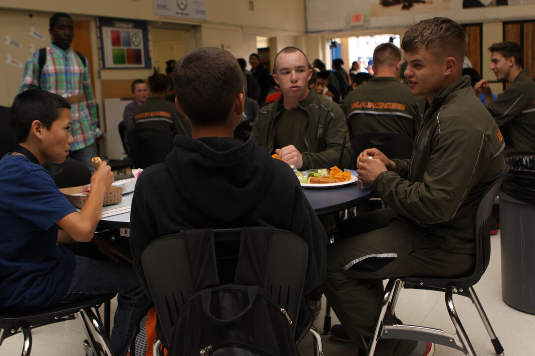 Camp Penldeton Marines take a break to eat lunch and converse with students from Jefferson Middle School after hosting a Marine Corps Physical Education Fitness Challenge, March 29. During each physical education class, hundreds of students gathered at the school's track and football field where Marine volunteers from Pendleton’s Single Marine Program held a four-station obstacle course.