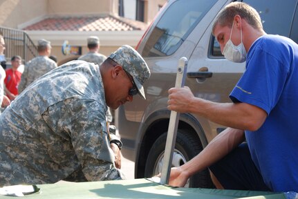 On right, Darryl Lawlor, 21, a student volunteer from the University of California, San Diego, receives instruction from a passing California National Guard soldier on how to set up cots to provide to hundreds of evacuees at the Del Mar Fairgrounds Tuesday.