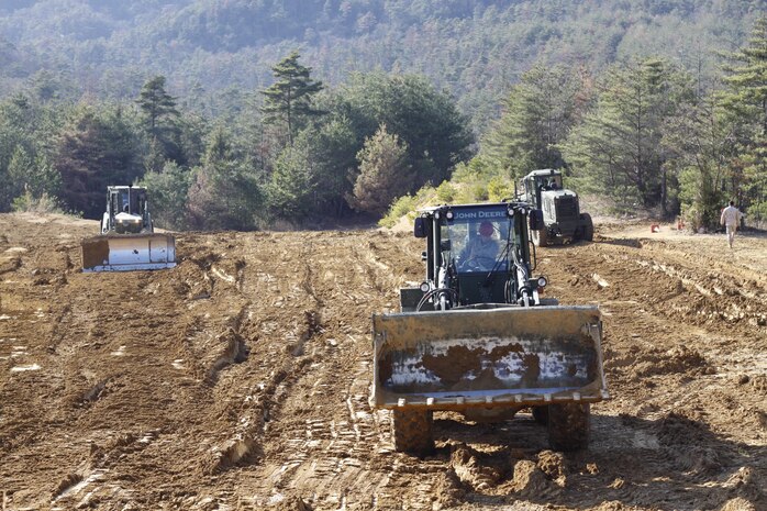 Marine Wing Support Squadron 171 heavy equipment operators replace the dirt they extracted practicing to build fighting positions and anti-tank trenches at the Haramura training area near Hiroshima during Exercise Thunder Horse, March 17-22, 2013. Weather added difficult obstacles for operators, as vehicles would get stuck in the mud and clay.