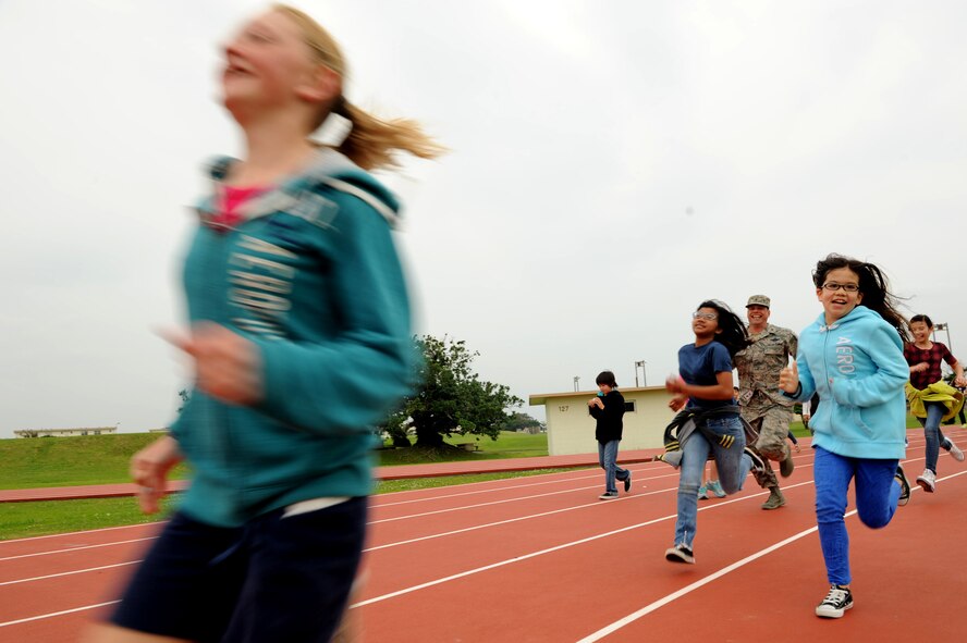 Kadena Middle School students race U.S. Air Force Brig. Gen. Matt Molloy, 18th Wing commander, during a wellness program event at the Risner Fitness Center track on Kadena Air Base, Japan, April 3, 2013. Students participated in a Hero Hike as part of their wellness program. The hike encourages physical activity for children for at least 45 minutes, and remembers past heroes. (U.S. Air Force photo by Airman 1st Class Hailey R. Davis/Released)