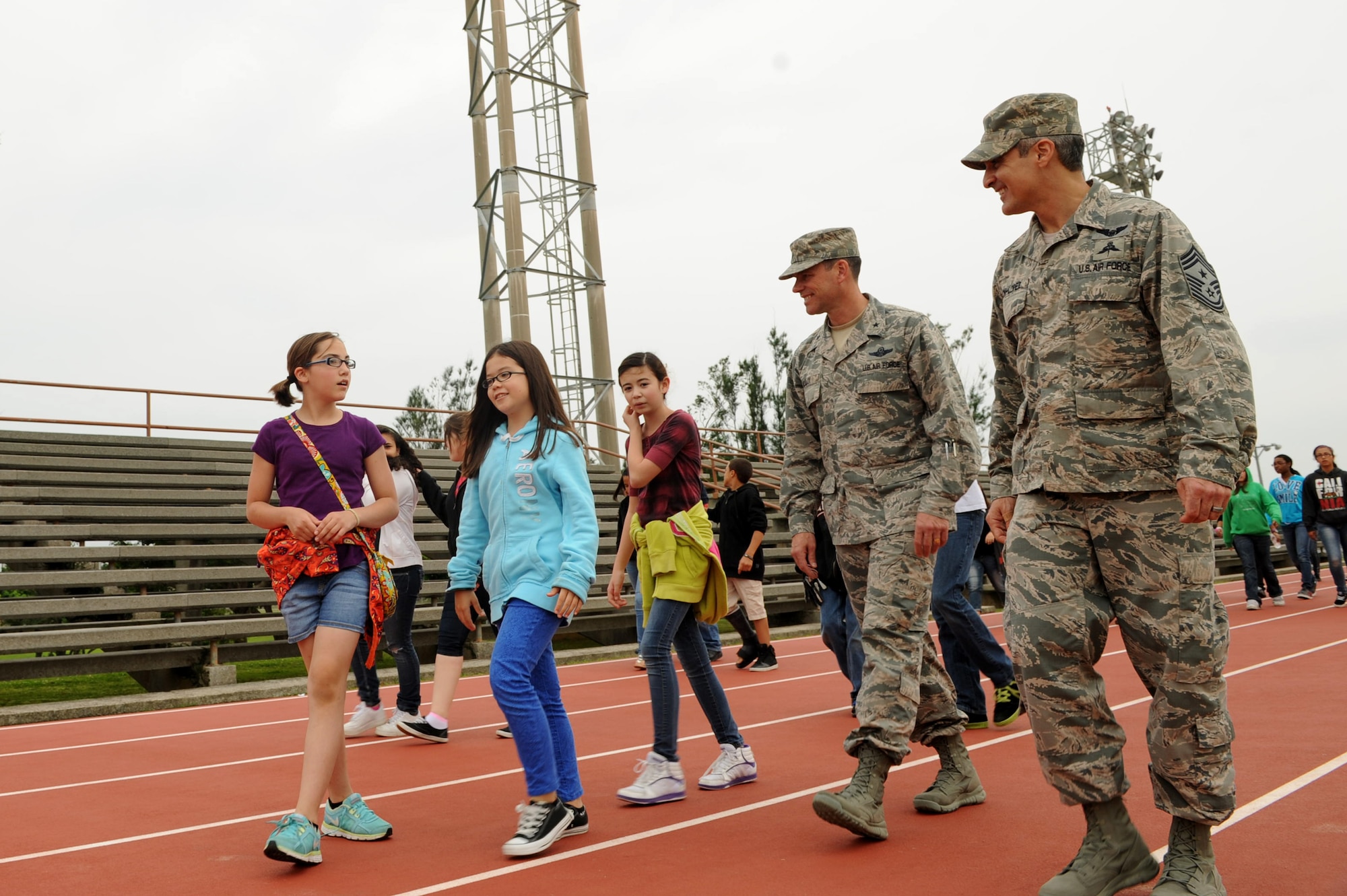 U.S. Air Force Brig. Gen. Matt Molloy, 18th Wing commander, and Chief Master Sgt. Ramon Colon-Lopez, 18th Wing command chief, speak with Kadena Middle School students during a wellness program event at the Risner Fitness Center track on Kadena Air Base, Japan, April 3, 2013. The Hero Hike encouraged students to participate in physical fitness outside the classroom and honored heroes of the past. (U.S. Air Force photo by Airman 1st Class Hailey R. Davis/Released)