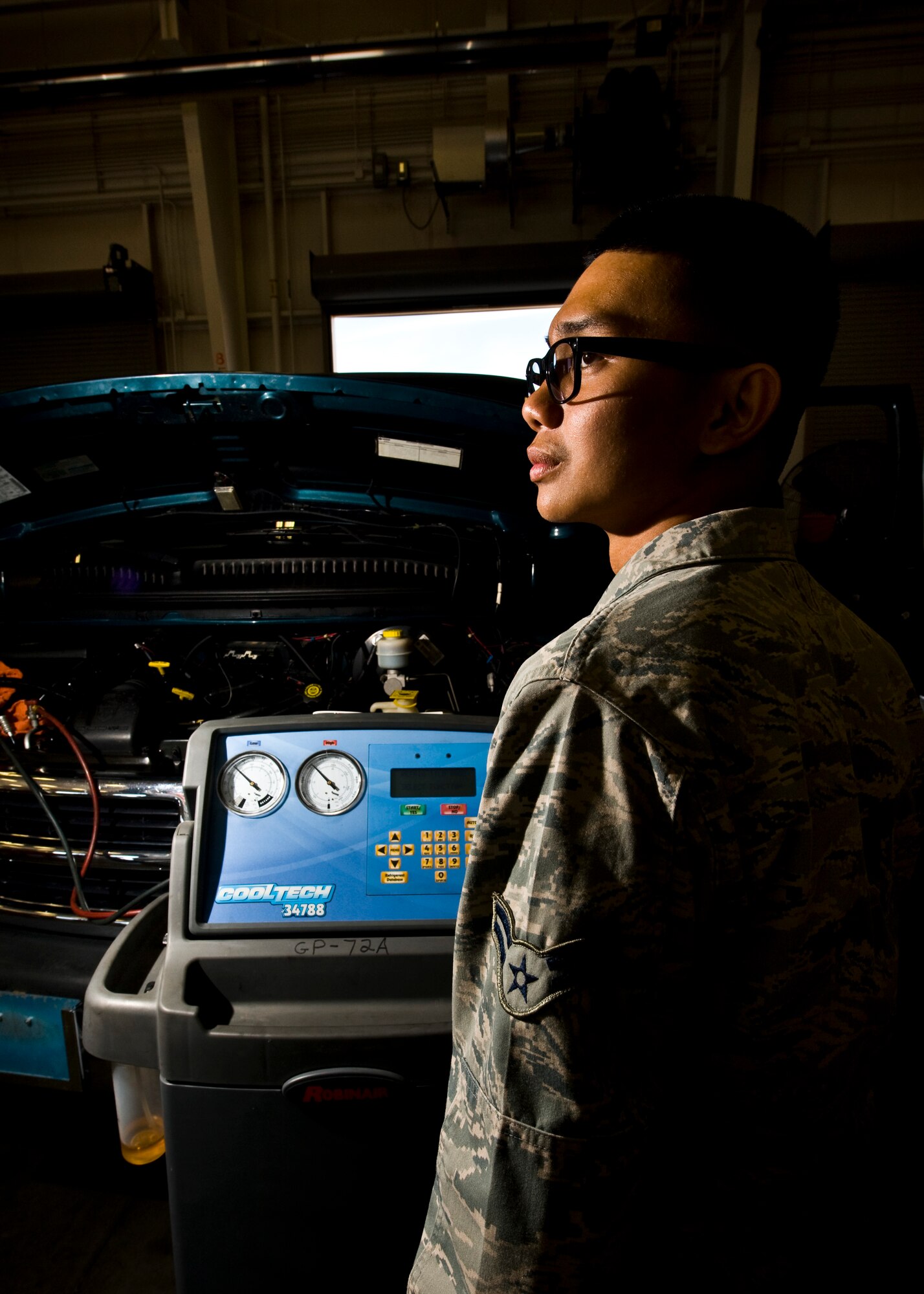 Airman 1st Class Lester Villarin, 99th Logistics Readiness Squadron vehicle maintenance specialist, charges the air-conditioner on a 16-passenger vehicle April 4, at the 99th LRS maintenance hangar. Maintaining the air-conditioners in the vehicles is important during the hot summers in Las Vegas. (U.S. Air Force photo by Staff Sergeant Michael Charles)

