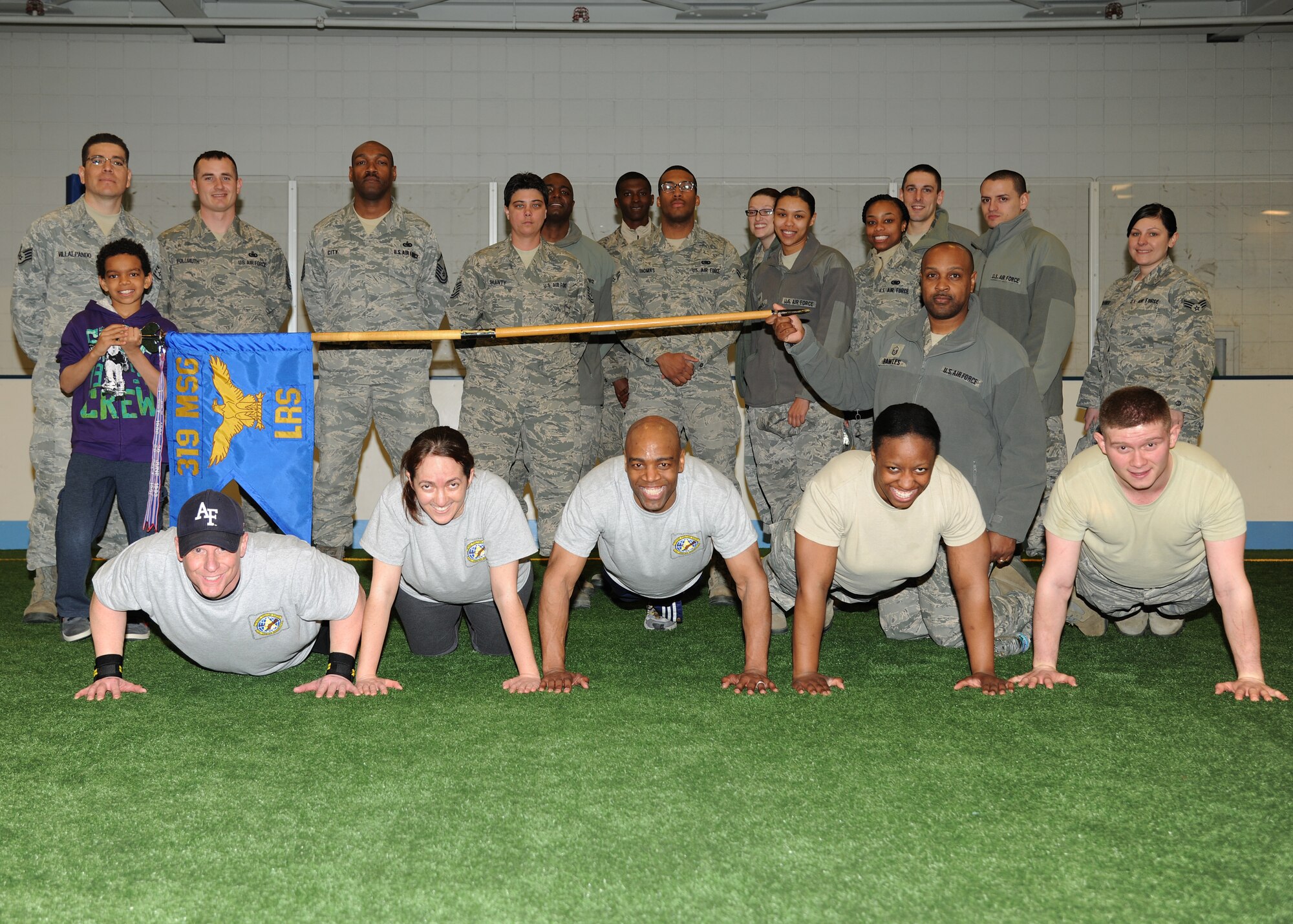 Family and military members from the 319th Logistics Rediness Squadron pose for a group photo after cheering on competitors several March 29, 2013, at the Sports and Fitness Center indoor soccer field on Grand Forks Air Force Base, N.D. The push-up competition helped raise funds for the Grand Forks AFB 1st Sergeants' Council's various charitable projects and programs. (U.S. Air Force photo/Airman 1st Class Ashley Nicole Taylor)