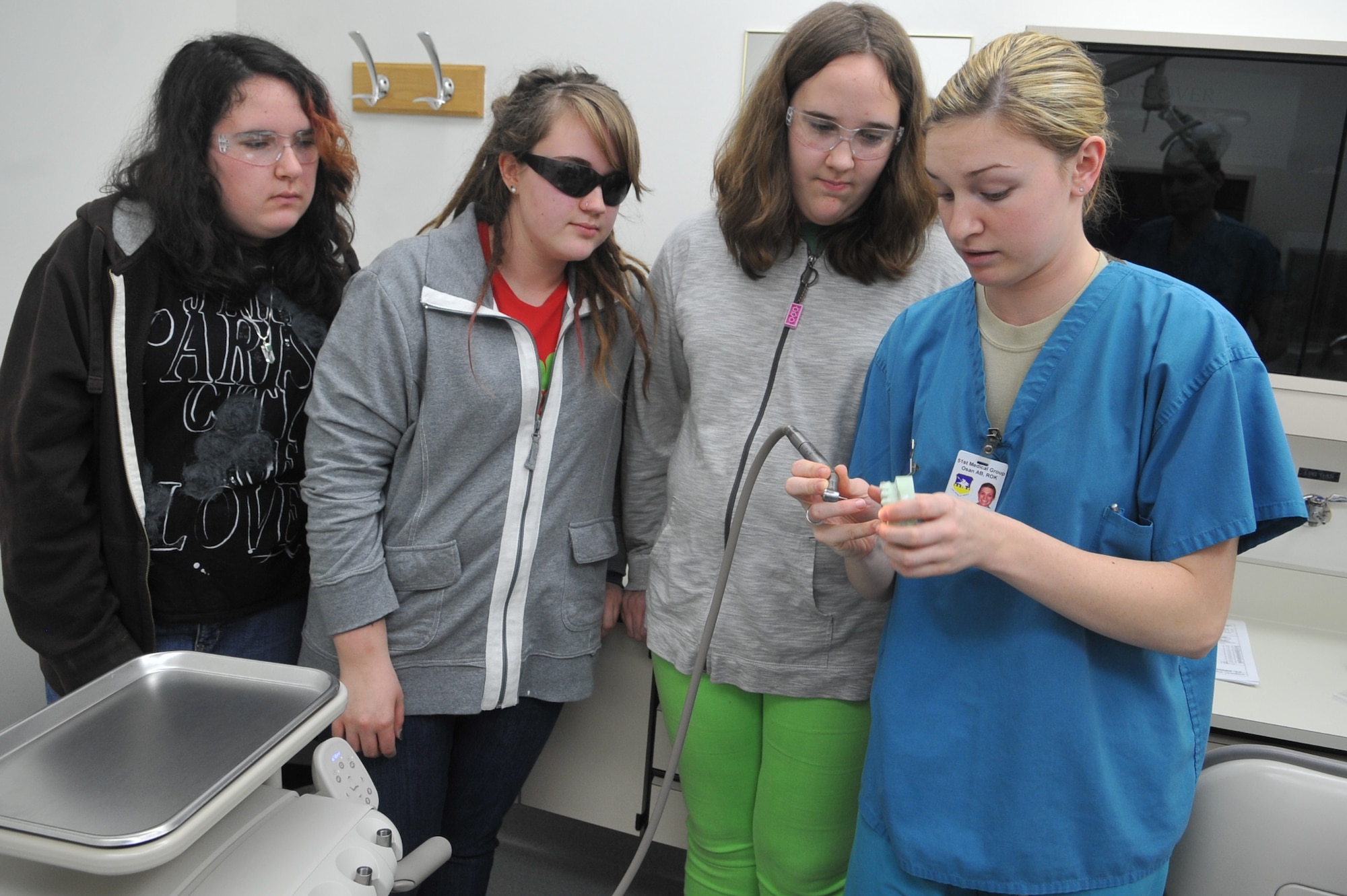 Jersha Price, Brianna Price and Lyberty Price watch as Senior Airman Sara Mula, 51st Medical Group dental assistant, demonstrates the proper use and technique of a dental drill at the hospital on Osan Air Base, Republic of Korea, April 2, 2013. The demonstration aimed to increase awareness in regards to dental health, as well as provide insight to those interested in dentistry as a career path. (U.S. Air Force photo/Tech. Sgt. Raymond Mills) 
