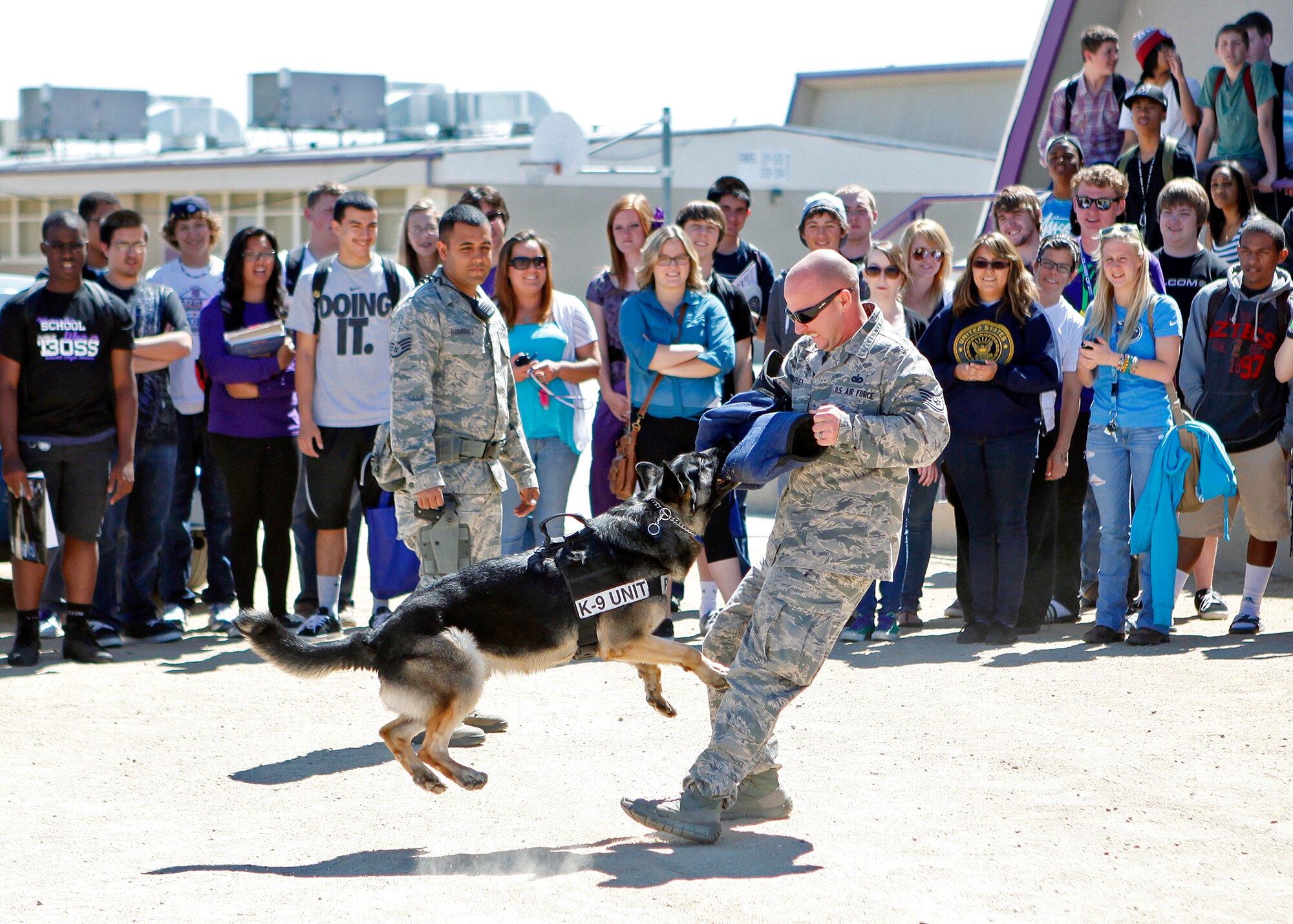 Staff Sgt. Brett Hurley, 412th Security Forces Squadron K-9 handler, displays the capabilities of a military working dog to a group of Desert High School students during the 2013 Career Fair at DHS March 28, 2013. The fair accomodated more than 500 students from DHS and Boron High School. (U.S. Air Force photo by Jet Fabara) 