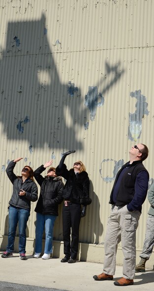 The shadow of an aircraft deicer falls on the building behind while a group of honorary commanders intently watch a demonstration of capabilites by the 436th Logistics Readiness Squadron/Heavy Equipment Flight, Dover Air Force Base, Del., March 28, 2013. Honorary commanders shown are:(l-to-r) Ms. Lori Ewald, 436th Comntracting Squadron, Judi Haughton, 436th Medical Dental Support Squadron, Ms. Beth B. Miller, 512th Security Forces Squadron, and Mr. Craig Weaver, 9th Airlift Squadron. A few lucky honorary commanders were able to experience operating the deicer for themselves.  Dover has a new batch of honorary commanders who, along with their military unit counterparts, received an in-depth tour and introduction to the capabilities of Dover AFB's functional units, March 28, 2013. (U.S. Air Force photo/Greg L. Davis)