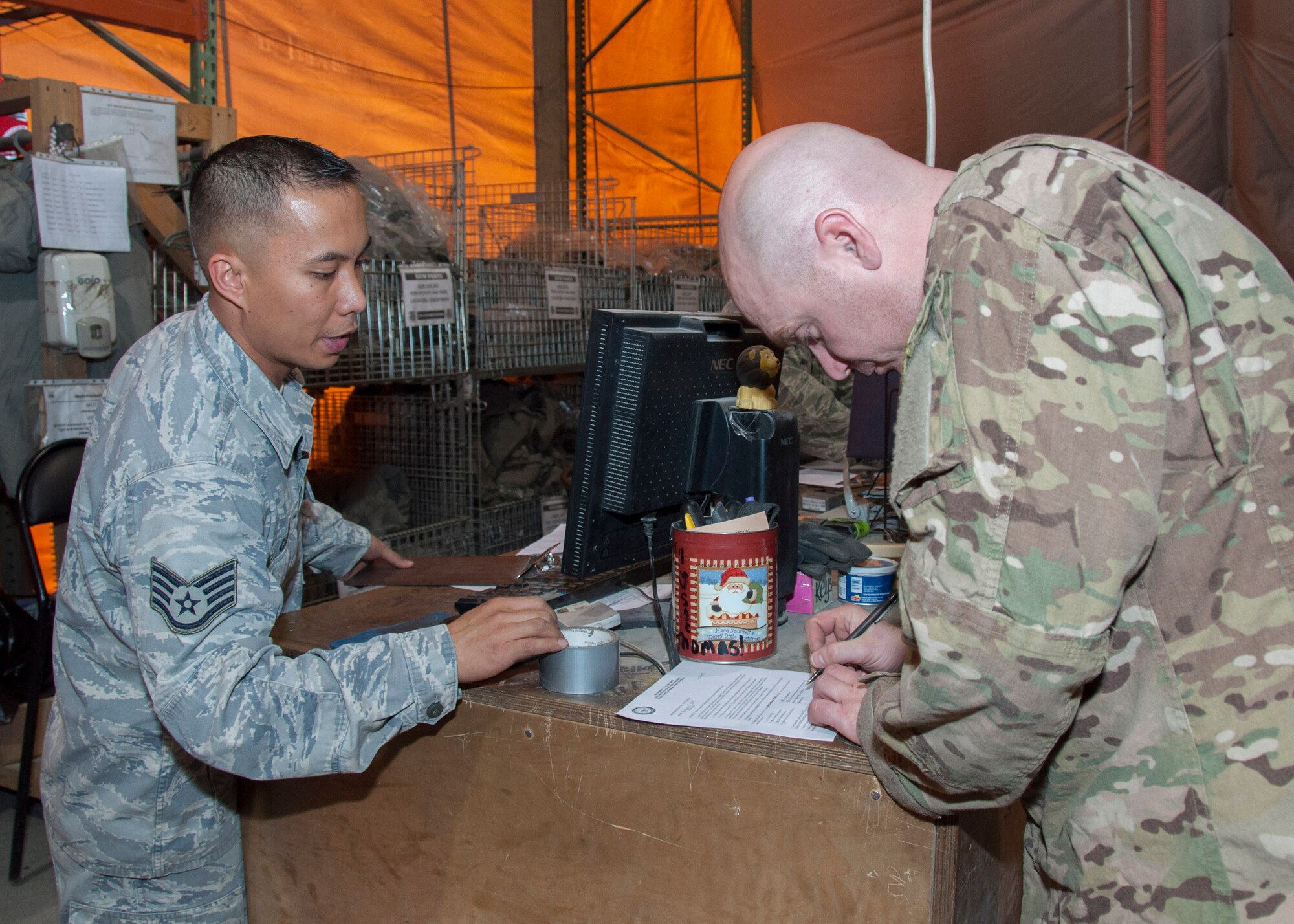 Staff Sgt. Teodoro Carla, 376th Expeditionary Logistics Readiness Squadron, assists a customer with paperwork required for equipment issue from the Expeditionary Theater Distribution Center March 29, 2013, at Transit Center at Manas, Kyrgyzstan. Deploying Airmen are issued protective vests and helmets, individual first aid kits, chemical protective ensembles, and cold-weather gear if needed. Carla is deployed from Nellis Air Force Base, Nev., and is a native of Redding, Calif. (U.S. Air Force photo/Tech. Sgt. Rachel Martinez)