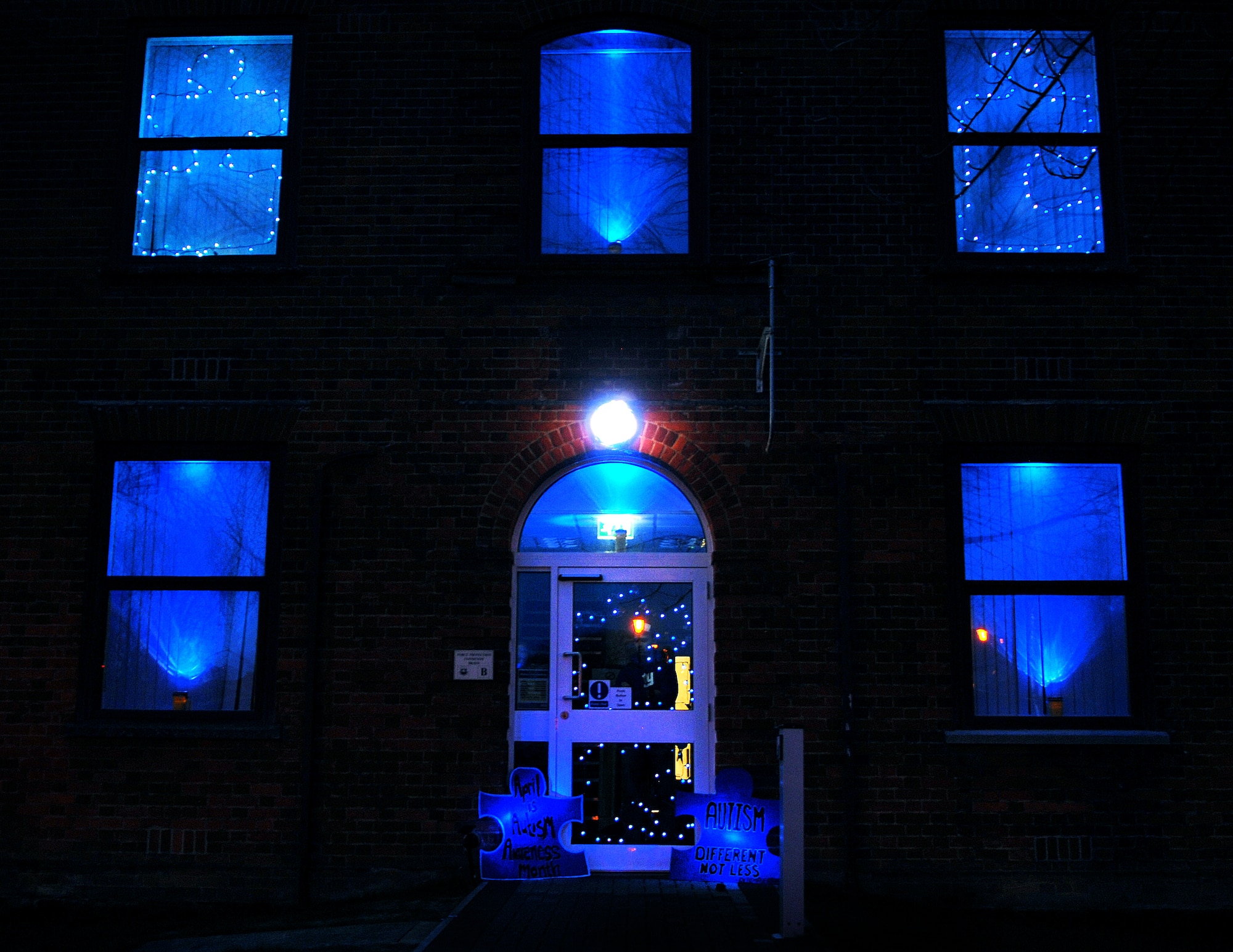 RAF Mildenhall’s Airman and Family Readiness Center lit up its building with blue lights April 2, 2013, to shine support on World Autism Awareness Day for the Autism Speaks’ Light It Up Blue campaign. Autism Speaks’ Light It Up Blue is a campaign to raise autism awareness and educate people about autism disorders. By modifying flashlights and spotlights with cellophane, and using Christmas lights to make puzzle pieces – the symbol for the campaign – the windows of the A&FRC shone blue to bring autism awareness to all of Team Mildenhall.  (U.S. Air Force photo by Airman 1st Class Dillon Johnston/released)