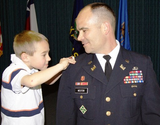 Lt. Col. Don Nestor smiles as his son carefully positions the shoulder strap with the silver oak leaf for the office of lieutenant colonel on his uniform during Nestor’s promotion ceremony. 