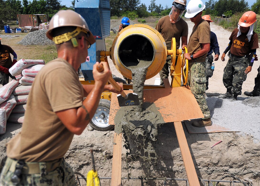 U.S. and Philippine Seabees pour concrete from a hand mixer onto the primary anchor of the San Pasqual footbridge's main support cable during construction of the San Pasqual footbridge in Zambales city, Philippines, March 27, 2013.