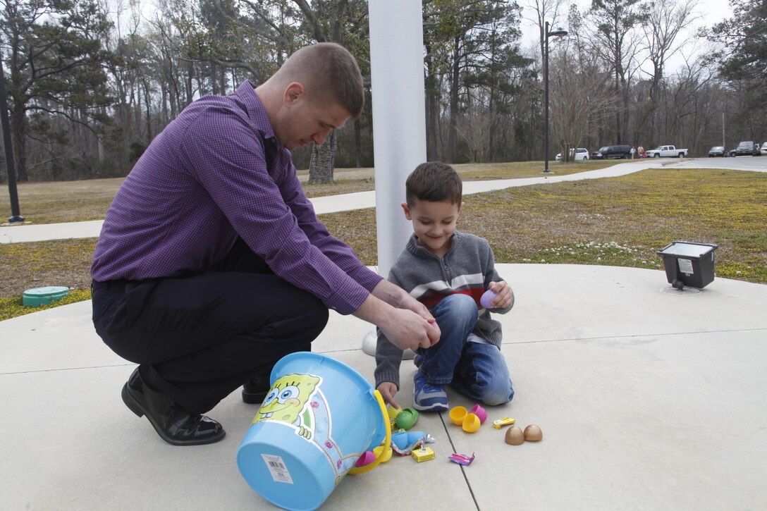 Lance Cpl. Bret White, a volunteer at the Easter egg hunt and his son crack open plastic eggs after the hunt at Miller's Landing Sunday.This was the first Easter White spent with his family. "I really think it raises morale with familieas getting loved ones together," he said.