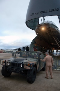 Master Sgt. Bob Mechan, a C-5 loadmaster with the New York Air National Guard, talks with Army Sgt. 1st Class Jason Rittichier, 1st Battalion, 228th Aviation Regiment, as he backs a humvee into the aircraft. A team of 19 Airmen and Soldiers and two helicopters from Joint Task Force-Bravo departed here Nov. 5 heading for the Dominican Republic to assist with recovery efforts in the wake of Tropical Storm Noel.