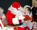 Richard Nashoalook of Wainwright, Alaska, smiles as he receives a gift from Santa Claus during Operation Santa Claus Nov. 26. The Alaska National Guard program delivers school supplies, presents and Santa Claus and Mrs. Claus to rural villages across the state.