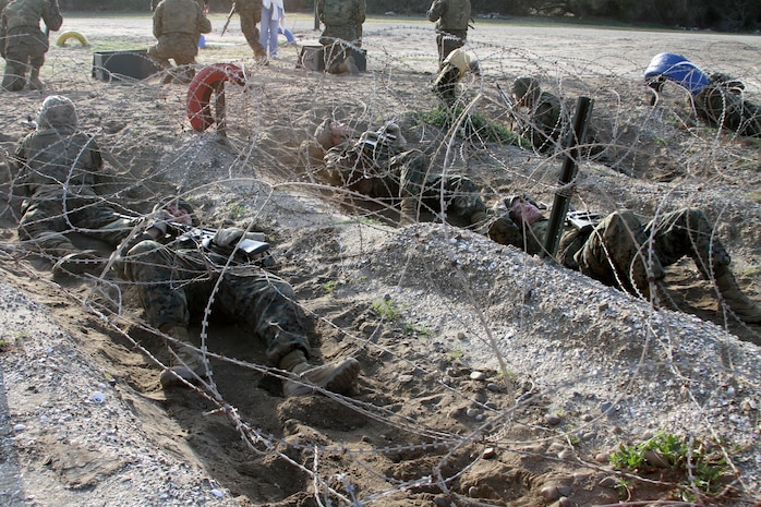 Recruits of Company L, 3rd Recruit Training Battalion, crawl on their backs to get across a barb wire obstacle during the Bayonet Assault Course aboard Marine Corps Recruit Depot San Diego March 19. Recruits must complete the course as part of a four-man fire team.
