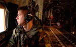 Tech. Sgt. Kyle Gurnon takes a seat next to the rear cargo door of a C-130 Hercules while taxiing for departure Jan. 9 at Ramstein Air Base, Germany, January, 9. Sergeant Gurnon is a Rhode Island Air National Guard loadmaster with the 143rd Airlift Wing at Quanset State Airport.