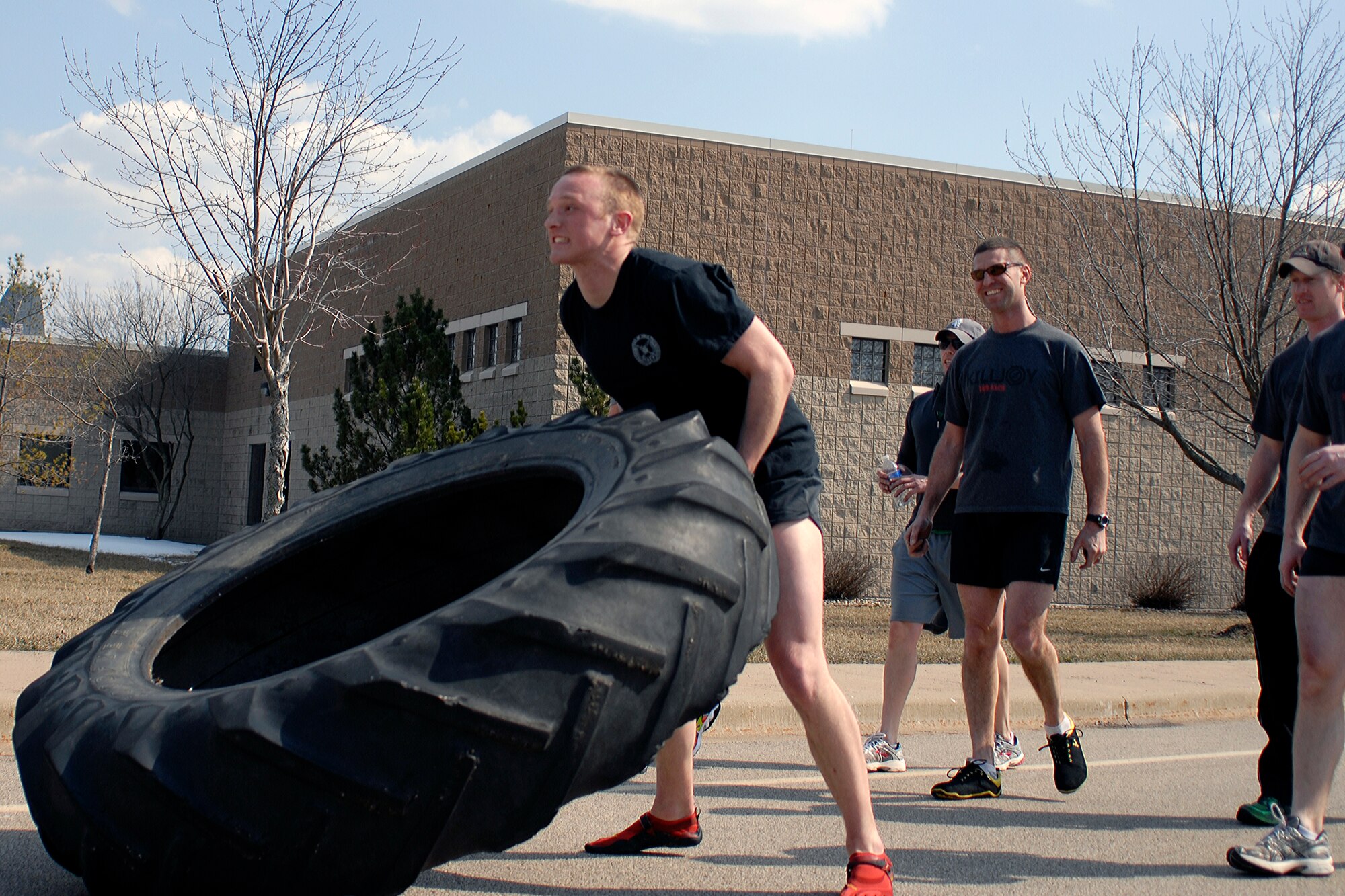 U.S. Air Force Senior Airman Nicolas Menz and fellow Tactical Air Control Party specialists flip a 230 pound tractor tire across the final lap of the TACP Association 24 Hour Run Challenge at the 182nd Airlift Wing in Peoria, Ill., March 29, 2013.  Sixty-two runners ran 161.75 miles around the installation over the course of 24 hours and raised over $8,200 in support of the TACP community and their families.  The 182nd team also ran in remembrance of Staff Sgt. Jacob Frazier, a member of the Peoria-based 169th Air Support Operations Squadron who was killed in action near Geresk, Afghanistan, exactly 10 years earlier.  (U.S. Air Force photo by Staff Sgt. Lealan Buehrer//Released)