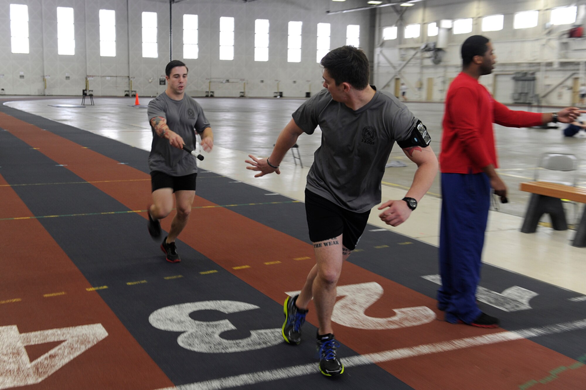 Senior Airman Eddie Schmitz, 3rd Air Support Operations Squadron radio operator, maintainer, and driver, hands off the baton to Senior Airman Ethan Brown, 3rd ASOS joint terminal attack controller, during a Tactical Air Control Party memorial run at Hangar 5 on Joint Base Elmendorf-Richardson, March 28, 2013. TACP members from JBER and Fort Wainwright ran a combined total of 216 miles in the 24 hour period. (U.S. Air Force photo/Staff Sgt. Zachary Wolf) 