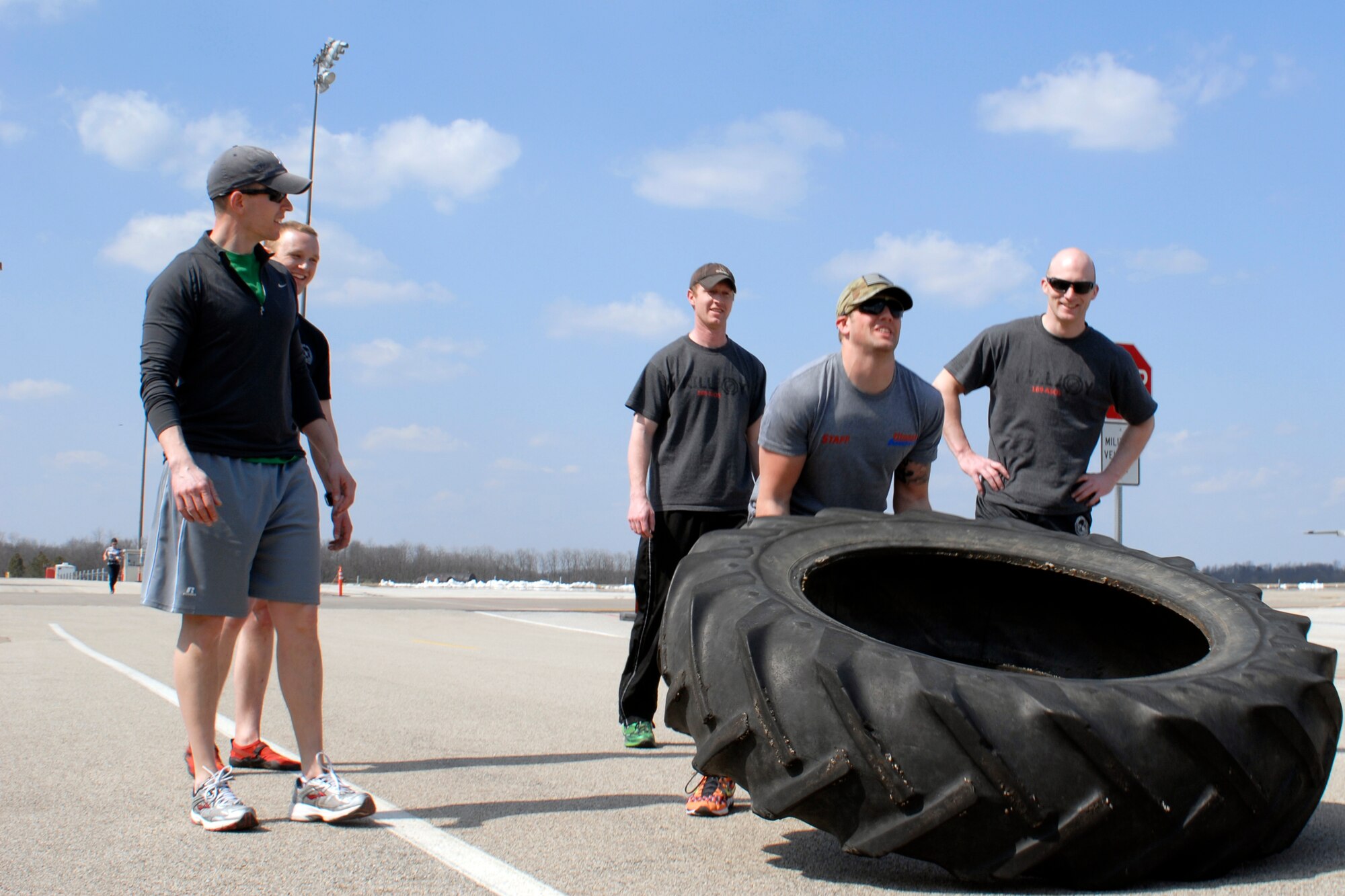 U.S. Air Force Senior Airman Cody Canfield and fellow Tactical Air Control Party specialists flip a 230 pound tractor tire across the final lap of the TACP Association 24 Hour Run Challenge at the 182nd Airlift Wing in Peoria, Ill., March 29, 2013.  Sixty-two runners ran 161.75 miles around the installation over the course of 24 hours and raised over $8,200 in support of the TACP community and their families.  The 182nd team also ran in remembrance of Staff Sgt. Jacob Frazier, a member of the Peoria-based 169th Air Support Operations Squadron who was killed in action near Geresk, Afghanistan, exactly 10 years earlier.  (U.S. Air Force photo by Staff Sgt. Lealan Buehrer//Released)(This image was cropped to emphasize the subject of the image.)