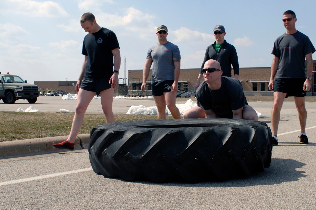 U.S. Air Force Staff Sgt. Nathan Adams and fellow Tactical Air Control Party specialists flip a 230 pound tractor tire across the final lap of the TACP Association 24 Hour Run Challenge at the 182nd Airlift Wing in Peoria, Ill., March 29, 2013.  Sixty-two runners ran 161.75 miles around the installation over the course of 24 hours and raised over $8,200 in support of the TACP community and their families.  The 182nd team also ran in remembrance of Staff Sgt. Jacob Frazier, a member of the Peoria-based 169th Air Support Operations Squadron who was killed in action near Geresk, Afghanistan, exactly 10 years earlier.  (U.S. Air Force photo by Staff Sgt. Lealan Buehrer//Released)