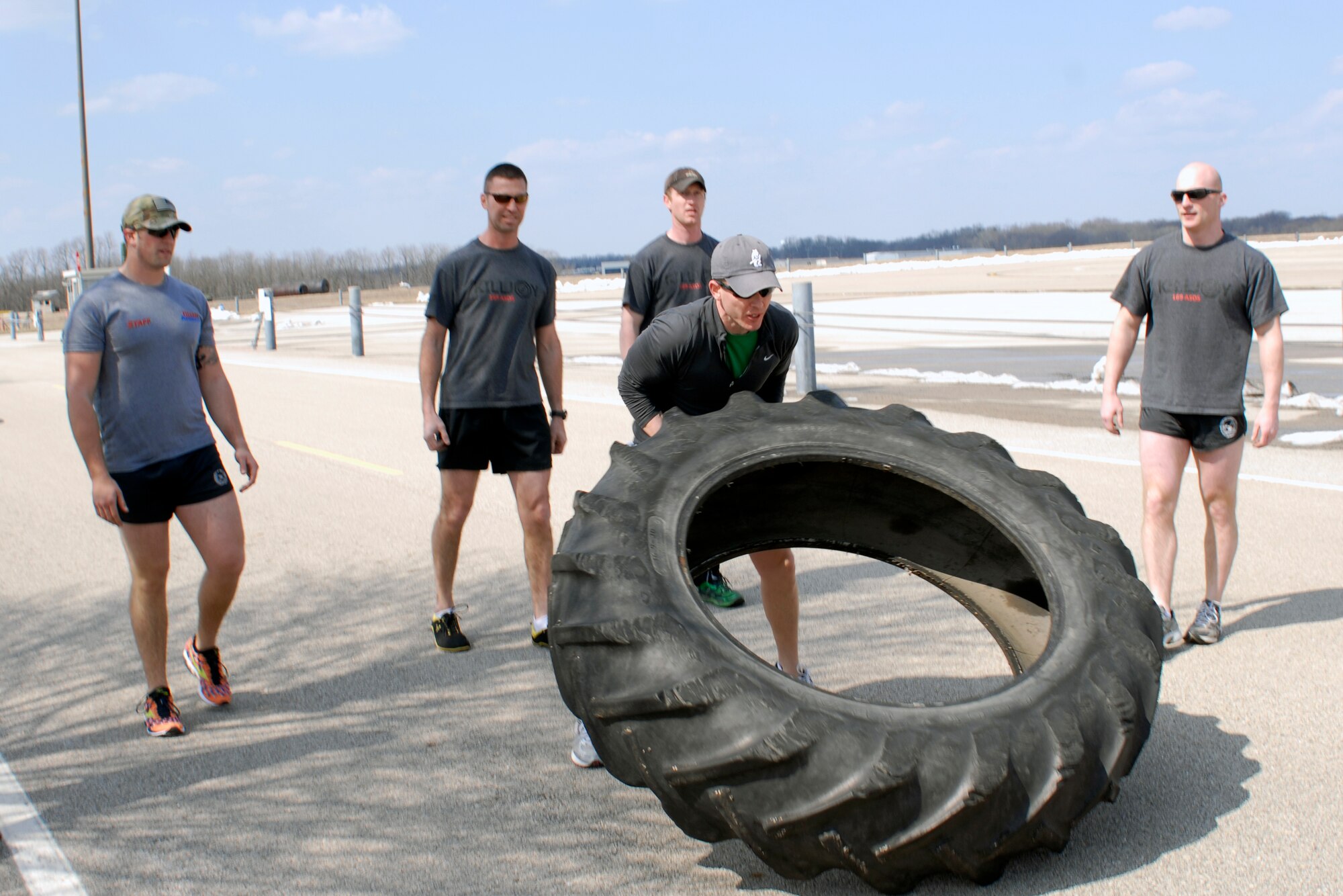U.S. Air Force Capt. Daniel Curtin and fellow Tactical Air Control Party specialists flip a 230 pound tractor tire across the final lap of the TACP Association 24 Hour Run Challenge at the 182nd Airlift Wing in Peoria, Ill., March 29, 2013.  Sixty-two runners ran 161.75 miles around the installation over the course of 24 hours and raised over $8,200 in support of the TACP community and their families.  The 182nd team also ran in remembrance of Staff Sgt. Jacob Frazier, a member of the Peoria-based 169th Air Support Operations Squadron who was killed in action near Geresk, Afghanistan, exactly 10 years earlier.  (U.S. Air Force photo by Staff Sgt. Lealan Buehrer//Released)