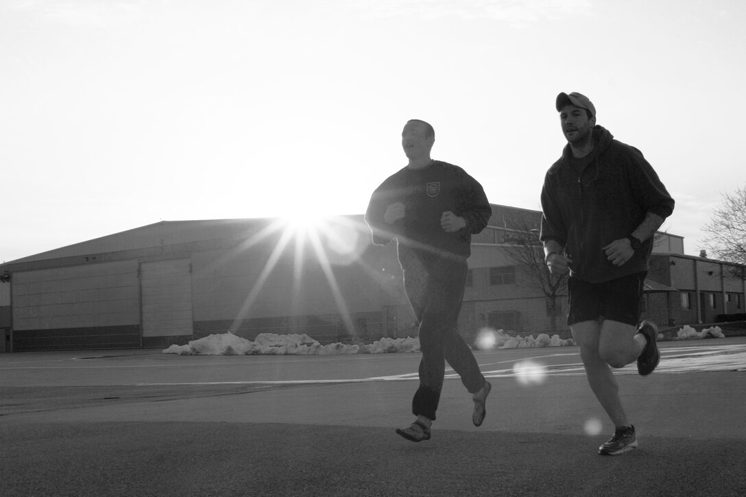 U.S. Air Force Senior Airmen Nicolas Menz, left, and Rob Design run past the sun setting on an aircraft hangar during the second annual Tactical Air Control Party Association 24 Hour Run Challenge at the 182nd Airlift Wing in Peoria, Ill., March 28, 2013.  Sixty-two runners ran 161.75 miles around the installation over the course of 24 hours and raised over $8,200 in support of the TACP community and their families.  The 182nd team also ran in remembrance of Staff Sgt. Jacob Frazier, a member of the Peoria-based 169th Air Support Operations Squadron who was killed in action near Geresk, Afghanistan, 10 years earlier on March 29, 2003.  (U.S. Air Force photo by Staff Sgt. Lealan Buehrer//Released)