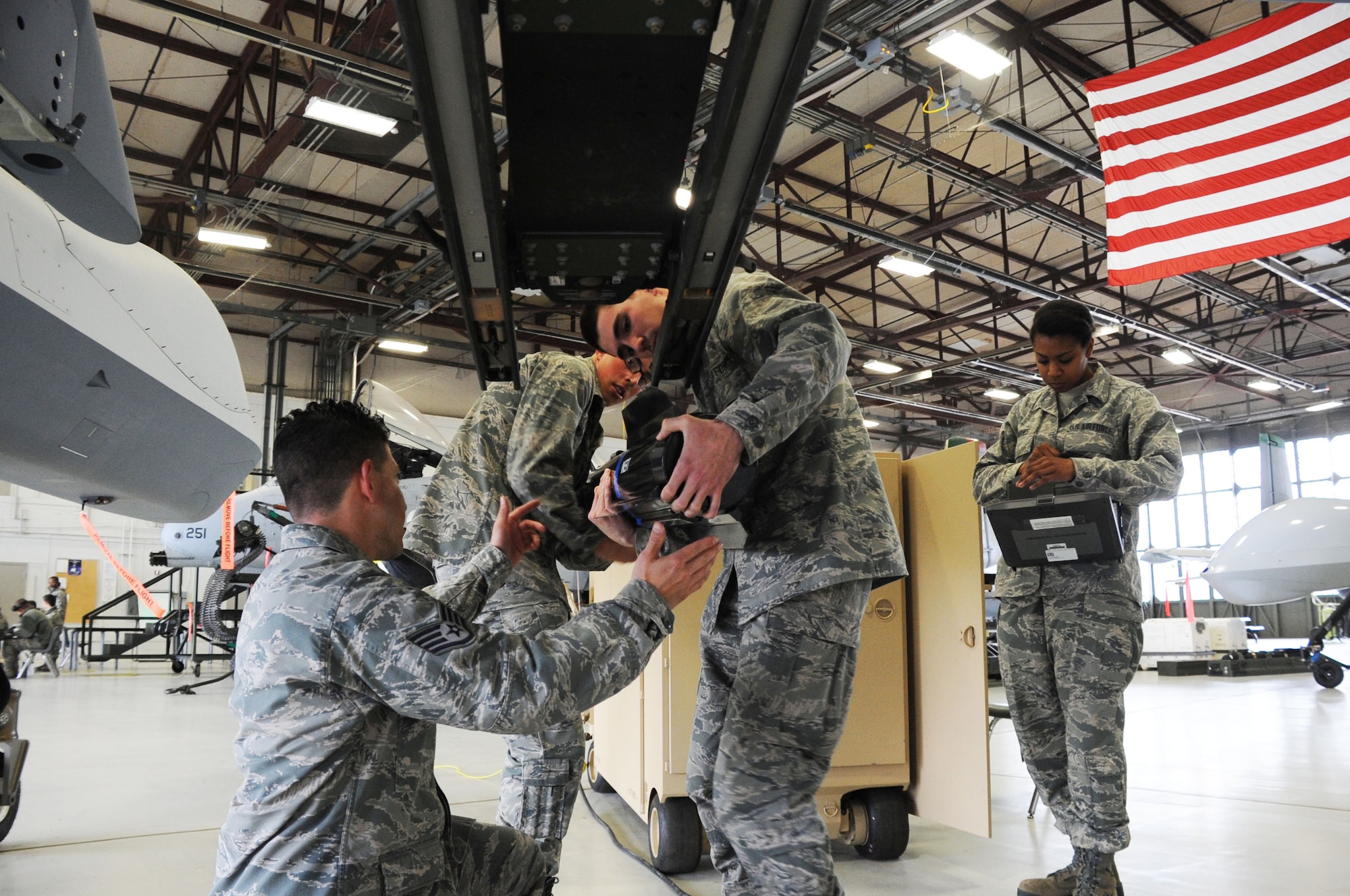 Airman Matthew Newman (2nd from right) and Ryan Bowen (3rd from right), remove a Hellfire missile from the MQ-9A Reaper under the watchful eye of Staff. Sgt. Ronel Rivera-Santiago (far left) during the 363rd Training Squadron's new Remotely Piloted Aircraft armament course at Sheppard Air Force Base, Texas, April 4, 2013.  The RPA armament course is 20 academic days long and will graduate its first class April 8.  (U.S. Air Force photo/Dan Hawkins) 