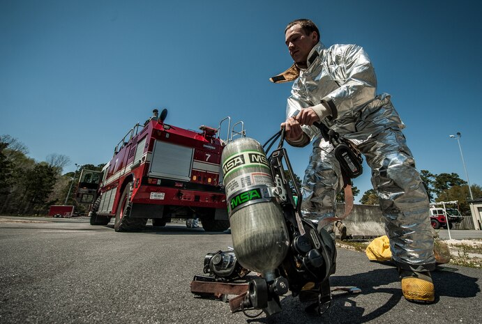 Airman 1st Class Michael Shonebarger, 628th Civil Engineer Squadron firefighter, dons his oxygen tank and gas mask during an aircraft, live-fire training exercise March 29, 2013, at Joint Base Charleston – Air Base, S.C. The base performs quarterly aircraft, live-fire training for firefighters and crew chiefs to maintain their qualifications. (U.S. Air Force photo/ Senior Airman Dennis Sloan)