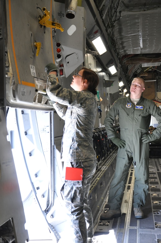 WRIGHT-PATTERSON AIR FORCE BASE, Ohio - Staff Sgt. Jaymes Cardwell instructs Airman 1st Class Stacey Scharf how to open and close the emergency exit door on a Cal Evacuation Squadron technician, sets up stanchions onboard a 445th Airlift Wing C-17 Globemaster III during a routine training mission March 14. Both are AES technicians assigned to the 445th Aeromedical Evacuation Squadron. (U.S. Air Force photo/Senior Airman Shen-Chia McHone)