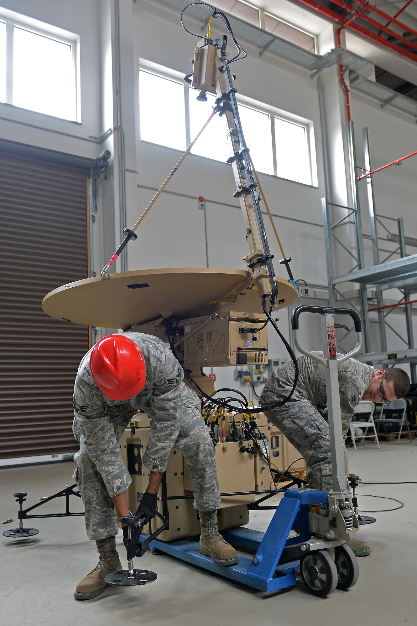 Senior Airman Howard Daniels, 1st Combat Communications Squadron radio frequency transmissions journeyman, and Airman 1st Class David Benavidez, 1st CBCS radio frequency transmissions apprentice, move equipment on Ramstein Air Base, Germany, March 25, 2013. Daniels was recently awarded the Thunderbolt award for his superior achievements and work performance. (U.S. Air Force photo/Airman 1st Class Holly Cook)