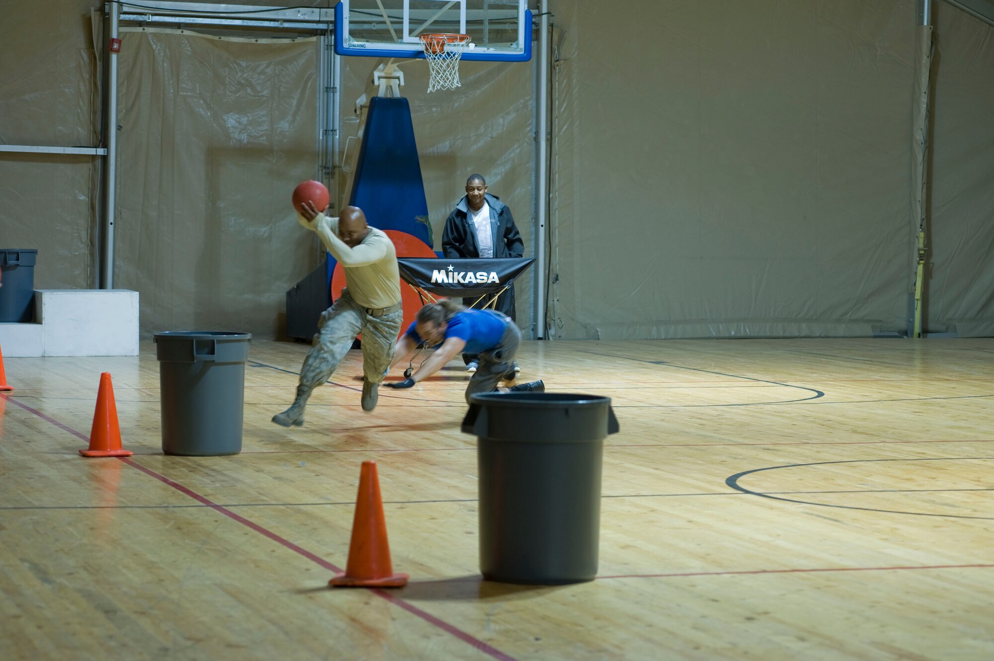 Staff Sgt. Bobby Humphrey, 376th Expeditionary Logistics Readiness Squadron Expeditionary Theater Distribution Center representative, runs from Wolf, American Gladiator, April 2, 2013, at Transit Center at Manas, Kyrgyzstan. Wolf is one of four American Gladiators touring with Billy Blanks to visit with deployed service members. (U.S. Air Force photo/Staff Sgt. Stephanie Rubi)