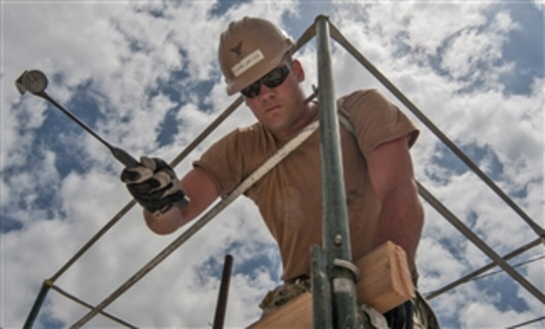 U.S. Navy Petty Officer 2nd Class Drake Van Blarcom builds a kick plate on top of scaffolding during the construction of a storage facility on Joint Base Pearl Harbor-Hickam, Hawaii, on April 2, 2013.  Blarcom is a Navy Seabee assigned to Construction Battalion Maintenance Unit 303.  