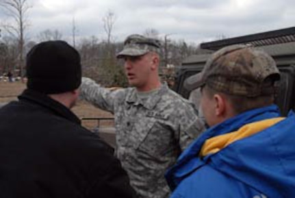 An Arkansas National Guardsman with the 2nd Battalion, 142nd Fires Brigade from Fort Smith assists residents of Atkins, Ark., following Tuesday night's devastating tornadoes.