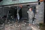 Lt. Col. James Treece, commander of the 217th Brigade Support Battalion, stands next to wreckage at Camp Shelby Joint Forces Training Center, Miss., March 3 caused by severe weather. Fourteen Soldiers with the Arkansas National Guard's 39th Infantry Brigade Combat Team were injured. Injuries were mainly limited to minor cuts and bruises, with one Soldier suffering a more severe, yet non-life-threatening injury.