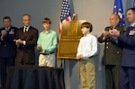 Alex and Joshua Stone (center) help unveil a bronze plaque March 14 etched with the image, name and story of their father, Maj. Gregory L. Stone, who died in Kuwait March 25, 2003. The ceremony at the Air Guard Readiness Center on Andrews Air Force Base, Md., dedicated the Air Guard's Crisis Action Team's (CAT) Stone Room. Stone served as the CAT's executive officer in 2001.