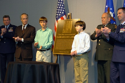 Alex and Joshua Stone (center) help unveil a bronze plaque March 14 etched with the image, name and story of their father, Maj. Gregory L. Stone, who died in Kuwait March 25, 2003. The ceremony at the Air Guard Readiness Center on Andrews Air Force Base, Md., dedicated the Air Guard's Crisis Action Team's (CAT) Stone Room. Stone served as the CAT's executive officer in 2001.