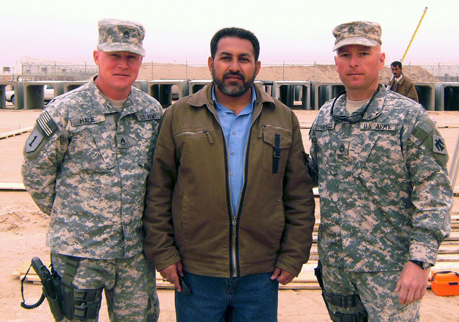 Army Staff Sgt. Russell Hale, left, Ali Jihad, an Iraqi construction supervisor, and Army Sgt. 1st Class Rafe Cummings stand in front of a construction site at Camp Bucca, Iraq.