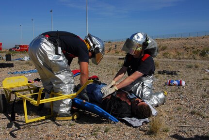 After a simulated plane crash, Senior Airmen Bruce Noble (left) and Michael Beller, firefighters assigned to the 162nd Fighter Wing, work together to evacuate a casualty during a major accident response exercise at Tucson International Airport.