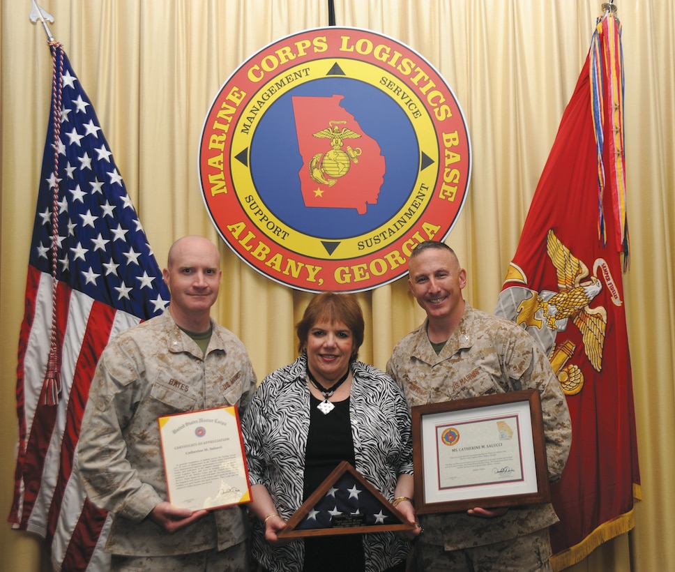 Catherine Salucci, traffic manager, Distribution Management Office, center, showcases her awards during her retirement March 21 with Col. Don Davis, commanding officer, MCLB Albany, right, and Lt. Col. Daniel Bates, executive officer, MCLB Albany.