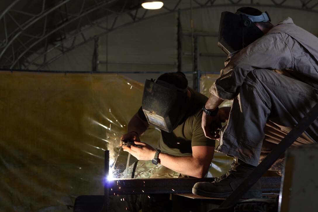 Cpl. Christopher Labrovic (right), a machinist with General Support Combat Logistics Company, Combat Logistics Regiment 2, supervises Craftsman Karl Lusardi (left), an armorer with 1 Close Support Battalion, Royal Electrical and Mechanical Engineers, as he practices welding in the GS CLC metal shop aboard Camp Leatherneck, April 3.
