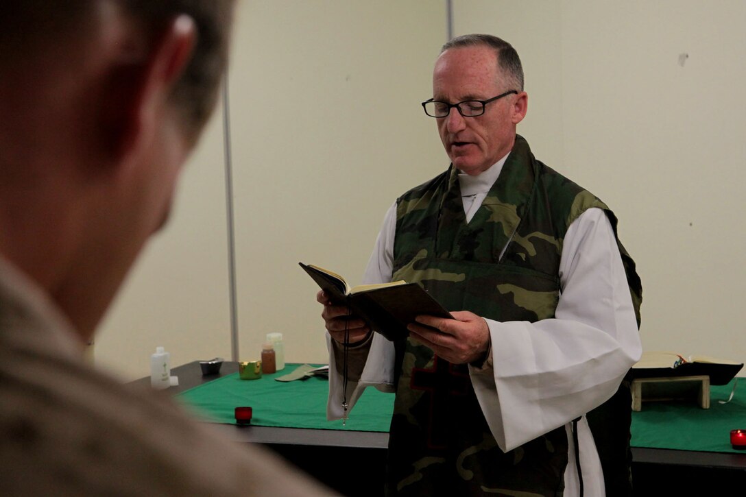 Captain Francis Foley, a Catholic priest and the 3rd Marine Aircraft Wing chaplain, reads a prayer during an Easter Mass here, March 30. Foley and Cmdr. Michael Williams, the Regimental Combat Team 7 chaplain, are traveling the area of operations to provide religious services and counseling to Marines and sailors during the Easter season.