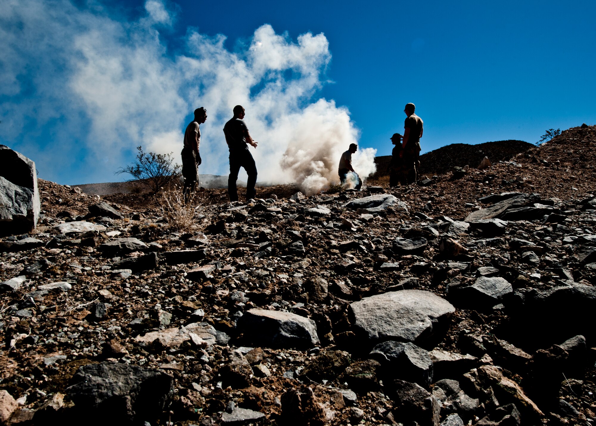 Tech. Sgt. Daniel Roman, 49th Operations Support Squadron survival, evasion, resistance and escape specialist, instructs students on how to make a smoke signal to attract rescue forces in Orogrande, N.M., March 13. By laying certain kinds of dense, living brush onto an open flame, a thick trail of smoke can be created as a signaling device over large distances. As a SERE specialist at Holloman Air Force Base, N.M., Roman is charged with teaching aircrew members many essential lessons about survival. (U.S. Air Force photo by Airman 1st Class Daniel E. Liddicoet/Released)