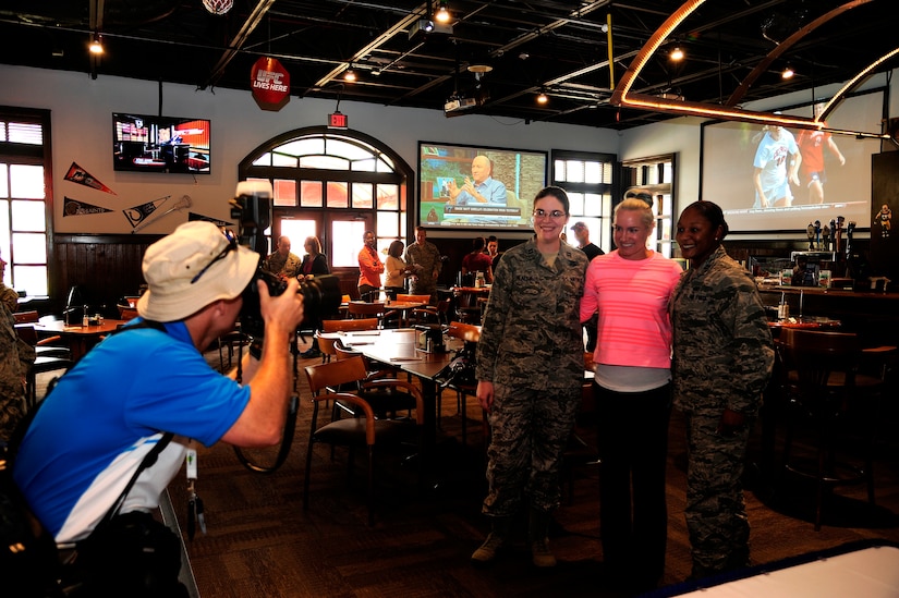 A Family Circle Cup photographer snaps a photograph of professional tennis player Bethanie Lynn Mattek-Sands, with Capt. Karen Mealey (left), 628th Force Support Squadron operations officer, and Capt. Elaine Christian, 628th FSS Sustainment Flight officer April 3, 2013, at Rookies Sports Grill at Joint Base Charleston – Air Base, S.C. Mattek-Sands was in Charleston competing in the Family Circle Cup tennis tournament and visited the Air Base to sign autographs for Team Charleston members and to tour a C-17 Globemaster III. (U.S. Air Force photo by Staff Sgt. Rasheen Douglas)
