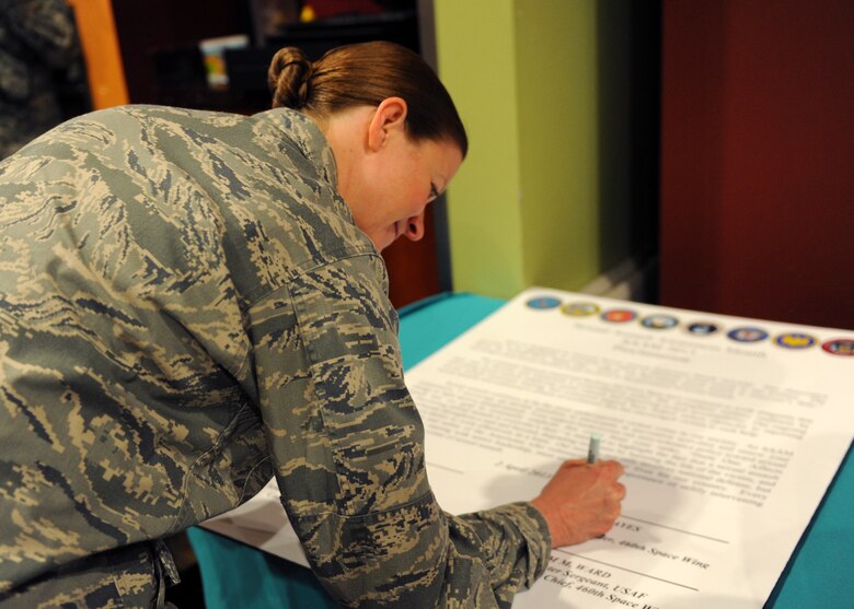 Col. Tracey Hayes, 460th Space Wing vice commander, signs the Sexual Assault Awareness Month proclamation April 2, 2013, in Centennial, Colo. The month of April is dedicated to raising awareness for sexual assault prevention. (U.S. Air Force photo by Senior Airman Marcy Glass/Released)
