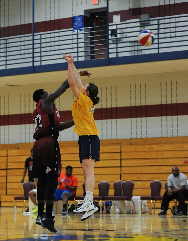 Maggie Hall, 28th Medical Operations Squadron physical therapyist, and Will Bell, Harlem Ambassadors basketball player, battles for possession during tipoff at the Bellamy Fitness Center on Ellsworth Air Force Base, S.D., March 26, 2013. More than 150 Airmen and family members were in attendance at the basketball show and were also given the opportunity to have photographs autographed by the Harlem Ambassadors following the game. (U.S. Air Force photo by Tech. Sgt. Jerry Fleshman/Released)